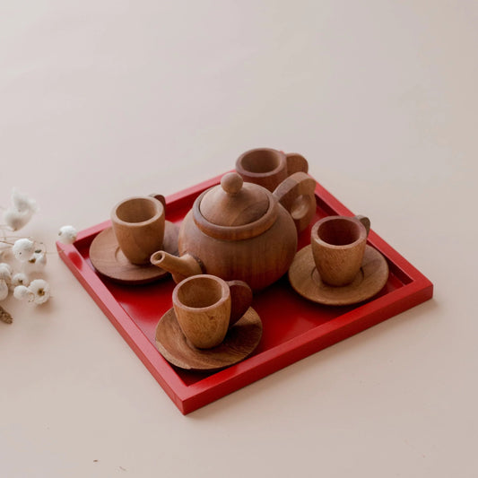 QToys Japanese wooden toy tea set with teapot, cups, and saucers on a red tray with white flowers in the background.