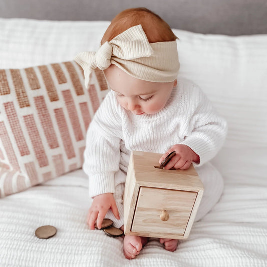 Baby playing with a QToys Montessori Object permanence box - disc drop box